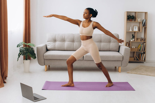 Kotimainen treenaus. Nuori urheilullinen musta nainen tekee lankku liikunta kotona, koulutus olohuoneessa - Valokuva, kuva