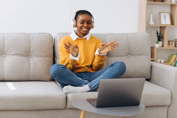 Fiatal afro-amerikai nő beszél videohívás a nappaliban otthon, távoktatási koncepció otthonról. - Fotó, kép