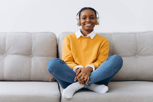 Nuori afroamerikkalainen nainen puhuu videopuhelu olohuoneessa kotona, etäopetuksen käsite kotoa. - Valokuva, kuva
