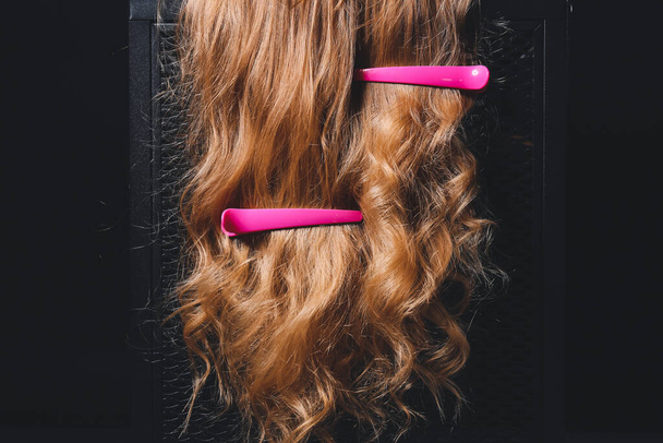 Жінка з кучерявим волоссям і шпильками на темному тлі
 - Фото, зображення