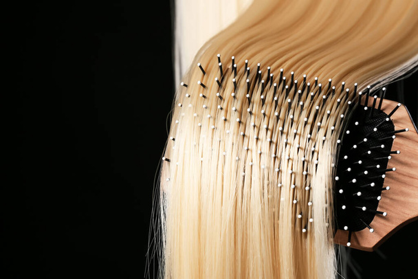 Escovação de longos cabelos loiros no fundo escuro - Foto, Imagem