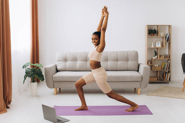 Kotimainen treenaus. Nuori urheilullinen musta nainen tekee lankku liikunta kotona, koulutus olohuoneessa - Valokuva, kuva