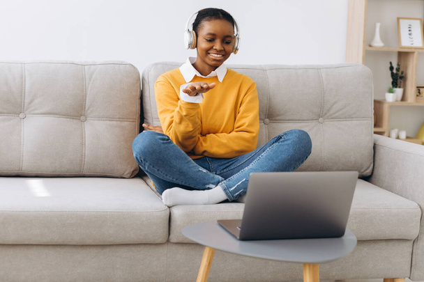 Junge Afroamerikanerin spricht per Videoanruf im heimischen Wohnzimmer, Fernstudium von zu Hause aus. - Foto, Bild