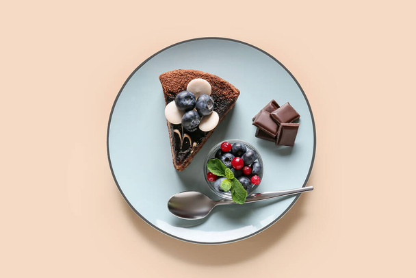 Placa con delicioso pedazo de pastel de chocolate y bayas sobre fondo claro - Foto, Imagen