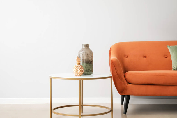 Stílusos barna kanapé és asztal vázákkal közel világos fal - Fotó, kép