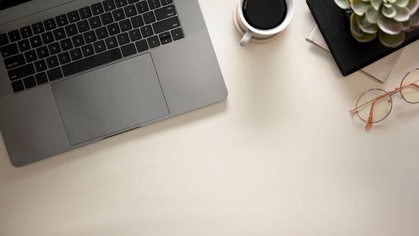 Moderno ufficio scrivania con computer portatile, occhiali, tazza di caffè, spazio copia, ombre di luce solare su sfondo bianco. Posa piatta, vista dall'alto - Foto, immagini