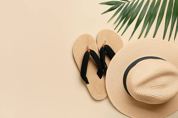 Stylish hat, flip-flops and palm leaf on color background - Photo, Image