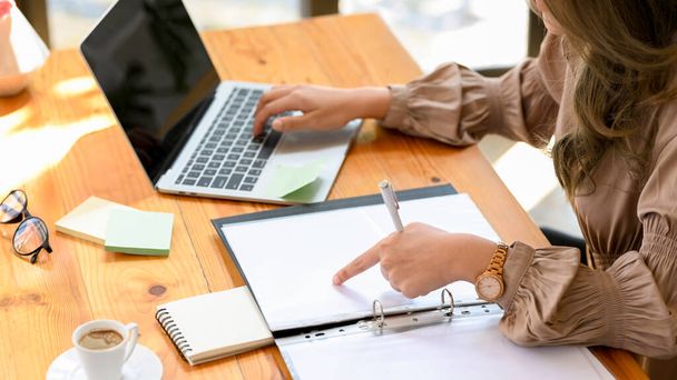 Przycięty obraz, bizneswoman lub kobieta księgowa pracująca na laptopie i dokumentów księgowych w biurze. - Zdjęcie, obraz