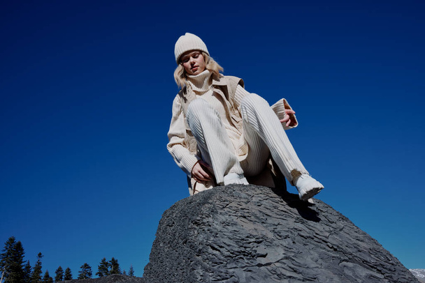 Женщина в осенней одежде стоит на скале пейзаж голубого неба образ жизни - Фото, изображение