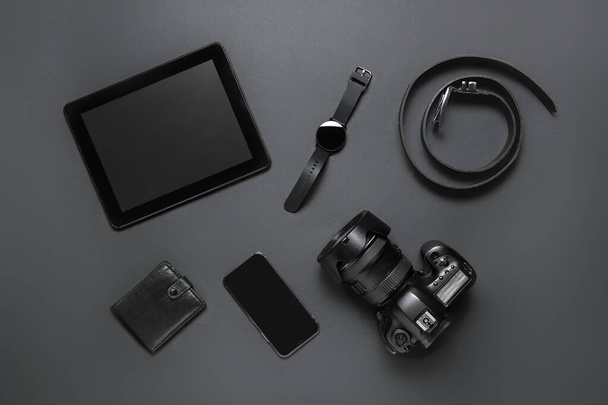 Set van moderne gadgets, riem en portemonnee op donkere achtergrond - Foto, afbeelding