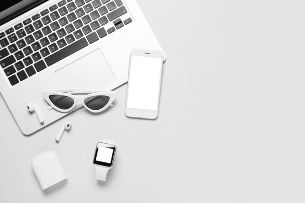 Modern laptop, mobile phone, earphones and sunglasses on white background - Photo, Image