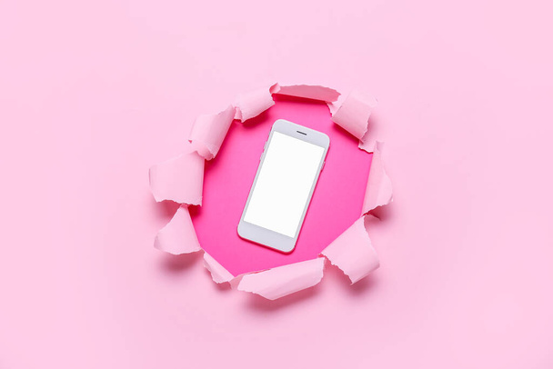 Téléphone portable visible à travers du papier couleur déchiré - Photo, image