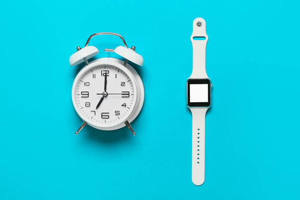 Reloj despertador y reloj inteligente sobre fondo de color - Foto, imagen
