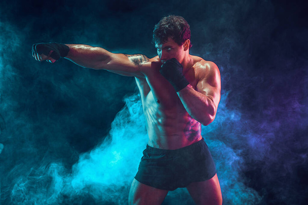 Half length of athlete boxer who training and practicing jab on smoke background. Sport concept - Foto, afbeelding