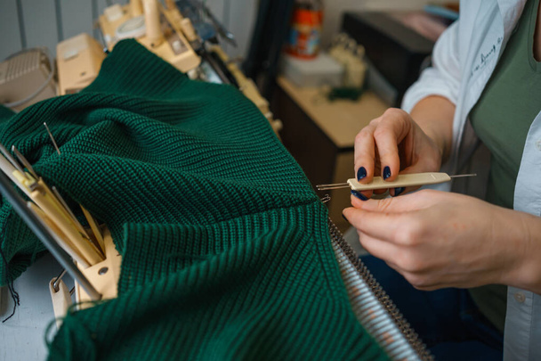 la persona è impegnata in lavorare a maglia su una macchina per maglieria familiare. lavoro manuale. Fatto a mano. Foto di alta qualità - Foto, immagini