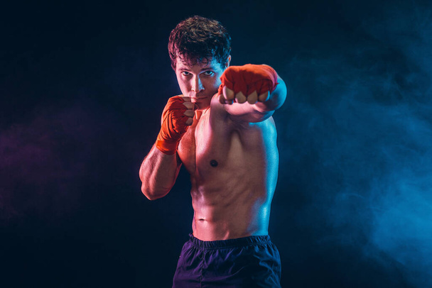 Front view of aggressive boxer who training and practicing jab on smoke background. Sport concept - Fotografie, Obrázek