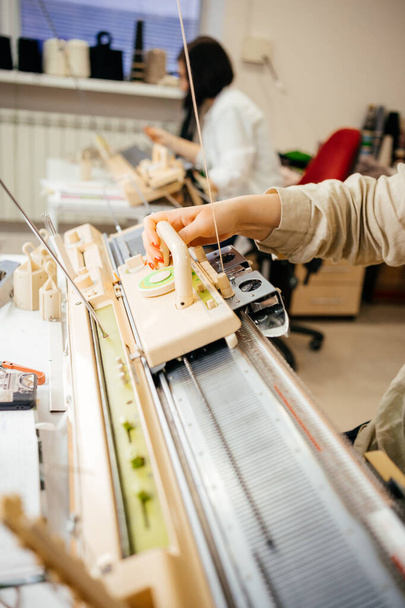 la personne est engagée dans le tricotage sur une machine à tricoter domestique. travail manuel. fait à la main. Photo de haute qualité - Photo, image