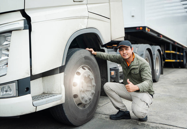 Asian Truck Driver Giving Thumb-Up and Checking Semi Truck Wheels Tires. Truck Inspection Maintenance and Safety Driving. - Фото, зображення