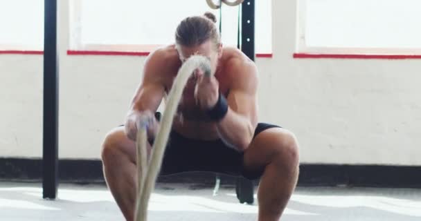 A csata csak saját magad ellen folyik. 4k videó egy izmos fiatalemberről, aki nehéz kötelekkel edz az edzőteremben.. - Felvétel, videó