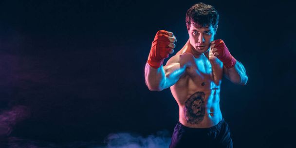 Half length of aggressive shirtless boxer who preparing for fight on dark background. Sport concept - Foto, Imagen