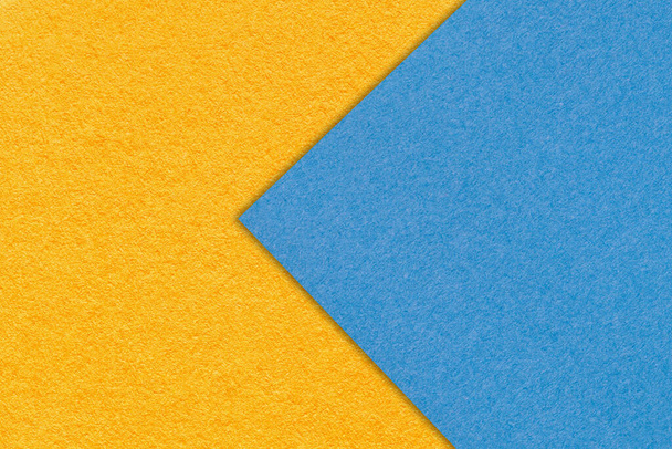 Текстура оранжевого и синего бумажного фона, половина двух цветов, макрос. Желто-небесно-триумфальная палитра. Структура плотного картона крафта. Фальшивый фон крупным планом. - Фото, изображение