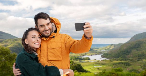 couple taking selfie on phone over irish landscape - Φωτογραφία, εικόνα