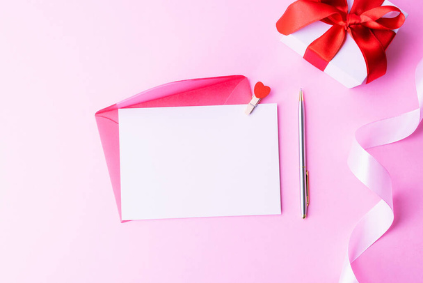 Muttertagsgeschenk. Frühling weiße Tulpenblume, Geschenk mit roter Schleife auf flachem, rosa Hintergrund. Valentinstag, Geburtstag, Frauen oder Hochzeitstag - Foto, Bild