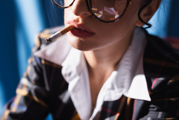 μερική άποψη του θολή vintage στυλ γυναίκα κάπνισμα σε μπλε φόντο - Φωτογραφία, εικόνα