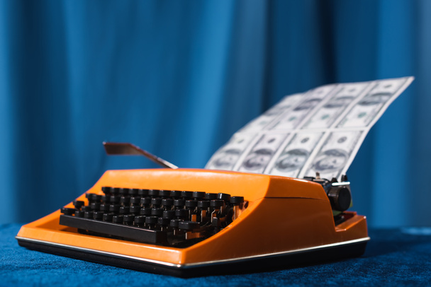 vintage psací stroj a rozmazané dolarové bankovky na modrém pozadí - Fotografie, Obrázek