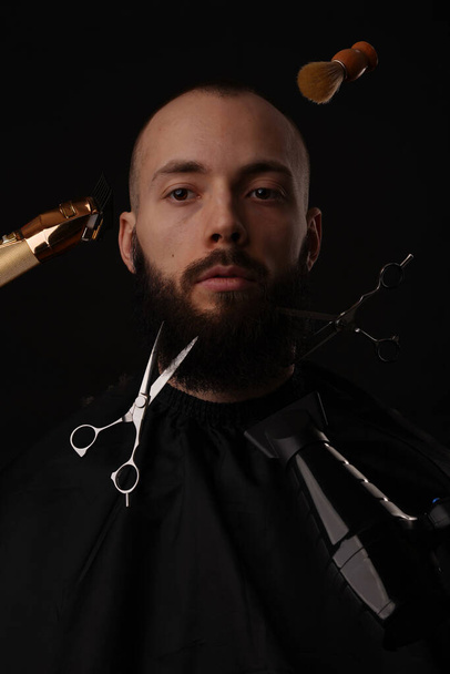 Tijeras, afeitadora y secador de pelo cortan el cabello y la barba del hombre - Foto, imagen