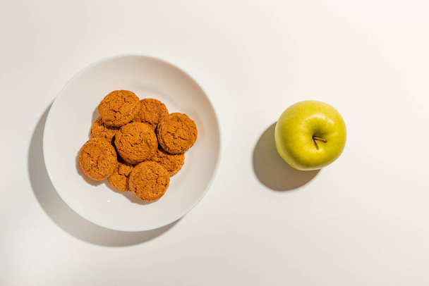 Cookies, Μπισκότα και πράσινο μήλο σε λευκό πιάτο πάνω όψη σε λευκό φόντο. - Φωτογραφία, εικόνα