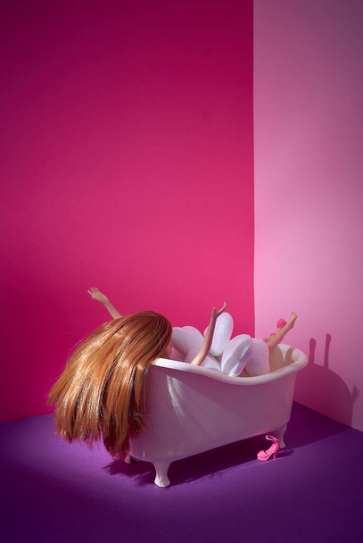 A tub full of white hearts. A female doll under hearts. Red hair. Pink shoes. Bright fuchsia purple pink background. Text space. Self-esteem, selfless, relaxation, lifestyle, concept. Minimal style. - Valokuva, kuva