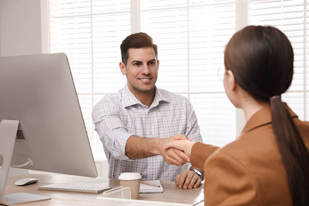 Employee shaking hands with intern in office - 写真・画像