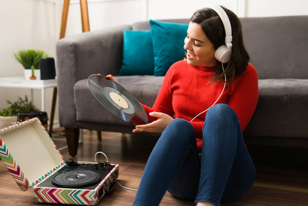 Music has saved me. Artistic woman sitting in the living room floor while enjoying music on vinyl records - Fotó, kép