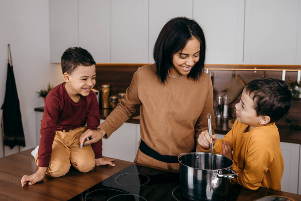 Onnellinen afrikkalainen amerikkalainen perhe äiti ja kaksi poikaa hauskaa ruoanlaitto lounas keittiössä - Valokuva, kuva