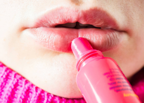женщина наносит розовый бальзам на губы закрыть, гигиеническая помада - Фото, изображение