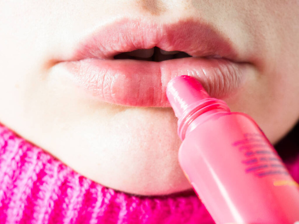 mujer aplicando bálsamo rosa en los labios de cerca, lápiz labial higiénico - Foto, Imagen