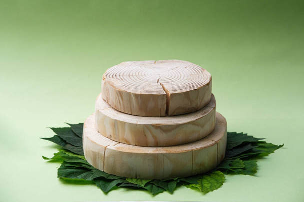 three round wooden sawn platform on green leaves background, geometric podium, mock up, eco scene for presentation of beauty cosmetic products - Photo, Image