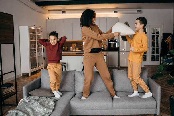 Felice afro americano famiglia mamma e due figli scherzare e fare cuscino battaglia - Foto, immagini