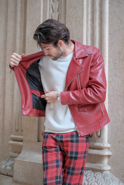 beautiful guy with red leather jacket and backpack in the center of reggio emilia. High quality photo - Photo, Image