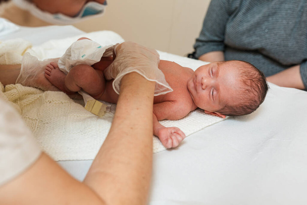 Φυσικοθεραπευτής εξετάζει ένα νεογέννητο μωρό σε ένα ιατρικό κέντρο. - Φωτογραφία, εικόνα