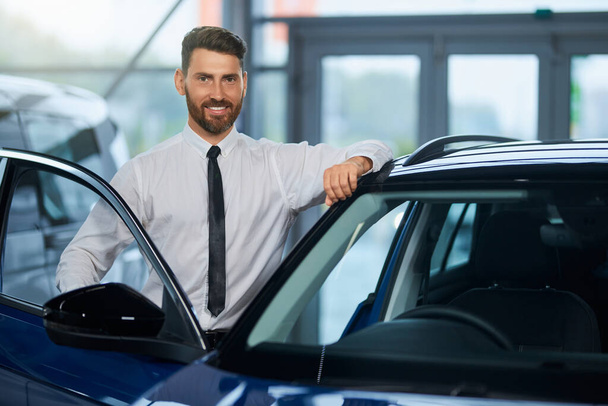 Businessman visiting auto salon for choosing new vehicle - Foto, afbeelding