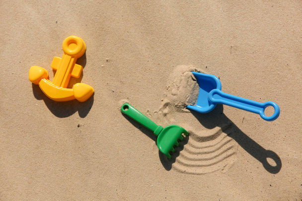 Set of plastic beach toys on sand, flat lay. Outdoor play - Foto, Imagem