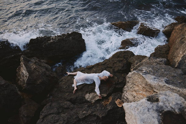 sensual woman lying on her back on a rocky seashore view from above - Photo, Image