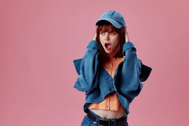 pretty woman in a cap and denim jacket posing color background unaltered - Photo, image