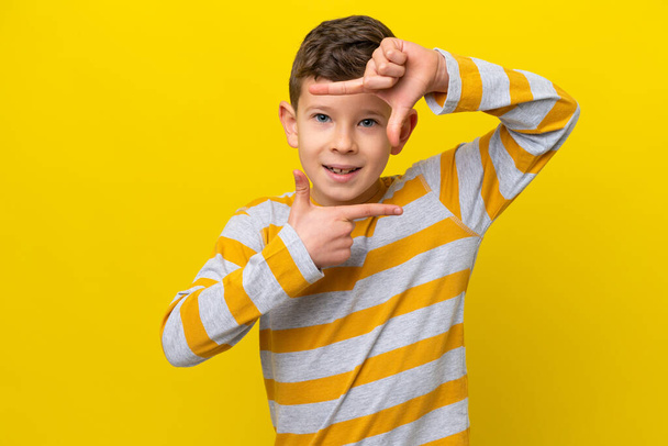 Маленький белый мальчик, изолированный на жёлтом фоне, сосредоточенный на лице. Символ обрамления - Фото, изображение