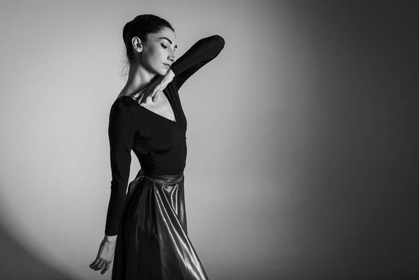 Een jonge elegante, emotionele balletdanseres, gekleed in professionele kleding, demonstreert haar dansvaardigheden, handbewegingen. De schoonheid van klassiek ballet. Slechte sleutel, foto Tsjernobyl - Foto, afbeelding