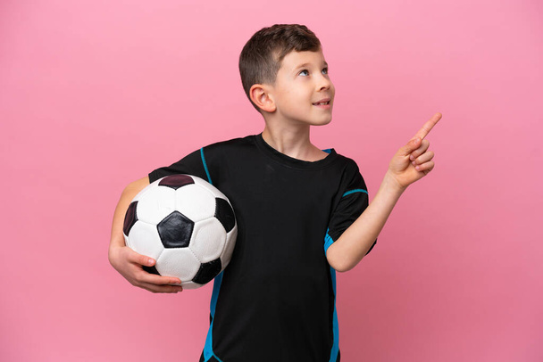 Маленький белый футболист, изолированный на розовом фоне, указывает на отличную идею. - Фото, изображение
