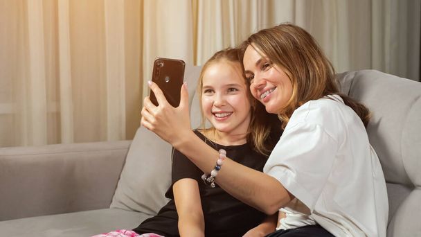 Mother and teen daughter make selfie in living room at home - Foto, Imagen
