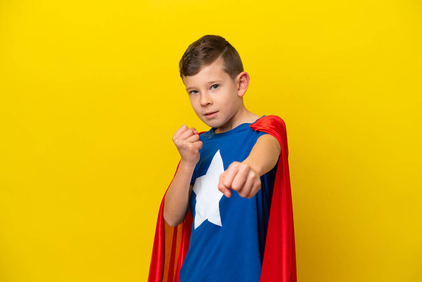 Little caucasian boy isolated on yellow background in superhero costume and fighting - Valokuva, kuva